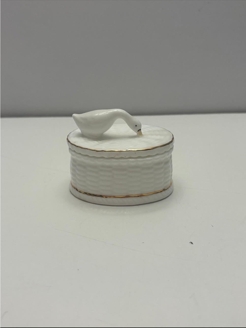 Vintage porcelain trinket box with a duck or goose on the lid and gold trim
